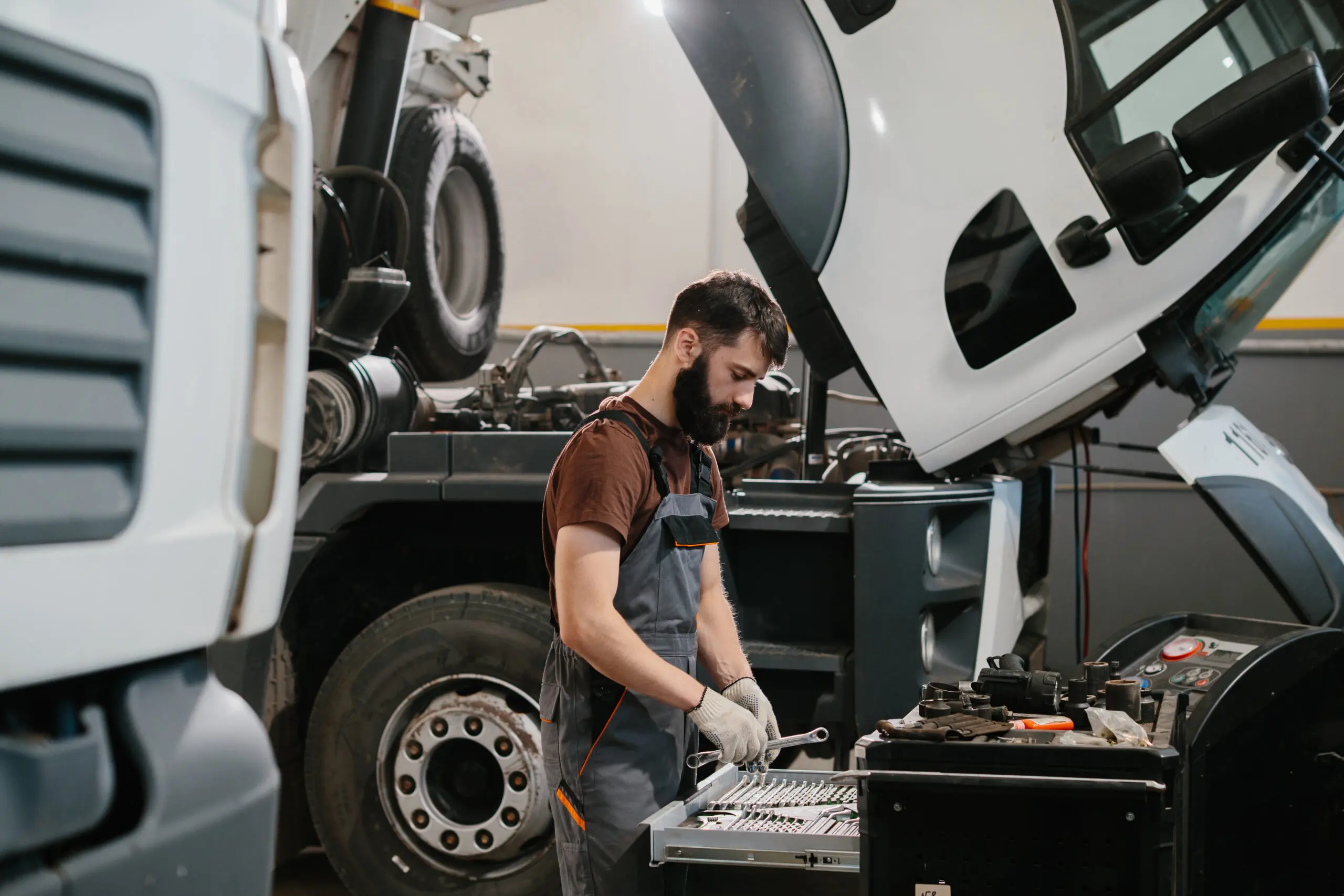 Professional auto mechanic choosing right wrench for repairing truck in garage